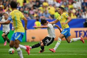Kaishu Sano (C) of Japan scores the 1-0 lead under pressure from Casemiro (R) of Brazil during the FIFA World Cup