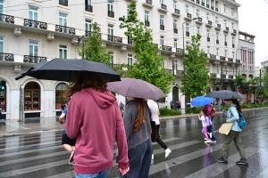 Κόσμος περπατά με ομπρέλες σε δρόμο της Αθήνας