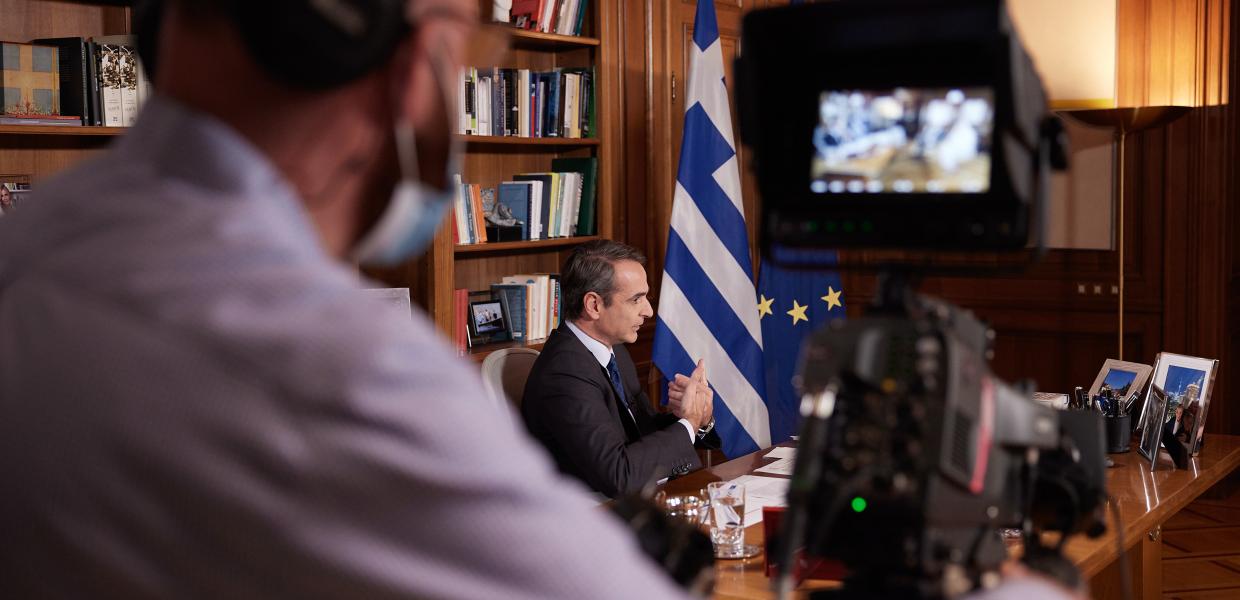 Κάμερα και στο βάθος ο Κυριάκος Μητσοτάκης
