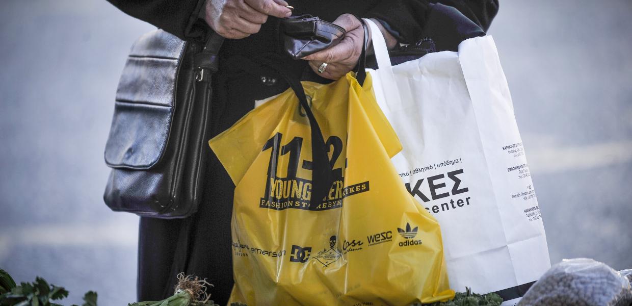 Ηλικιωμένη γυναίκα κρατάει πορτοφόλι και ψωνίζει σε λαϊκή αγορά των Τρικάλων.