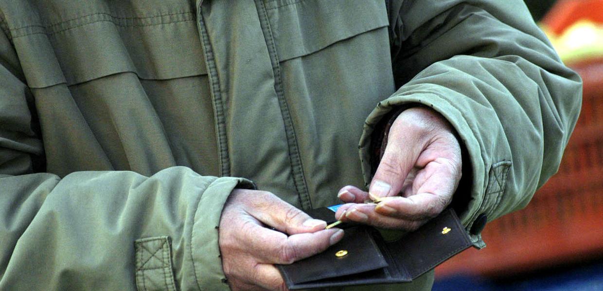 Άνδρας κρατάει πορτοφόλι και μετράει τα κέρματα.
