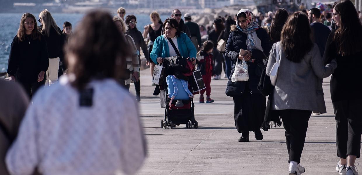 Κόσμος σε βόλτα δίπλα στη θάλασσα