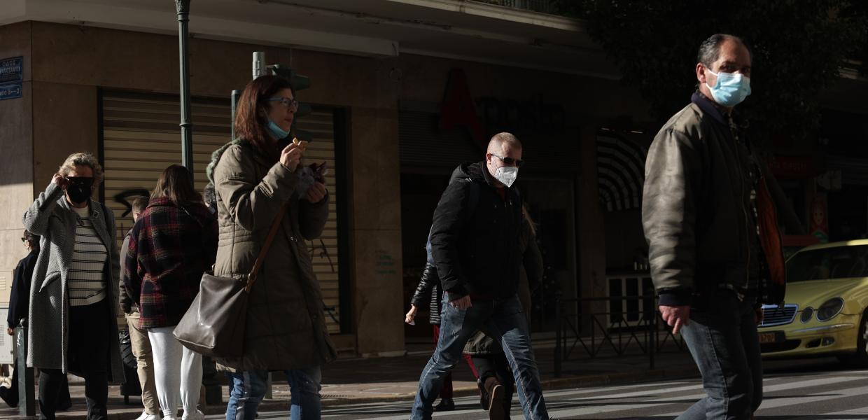 Άνθρωποι διασχίζουν το δρόμο φορώντας μάσκα 