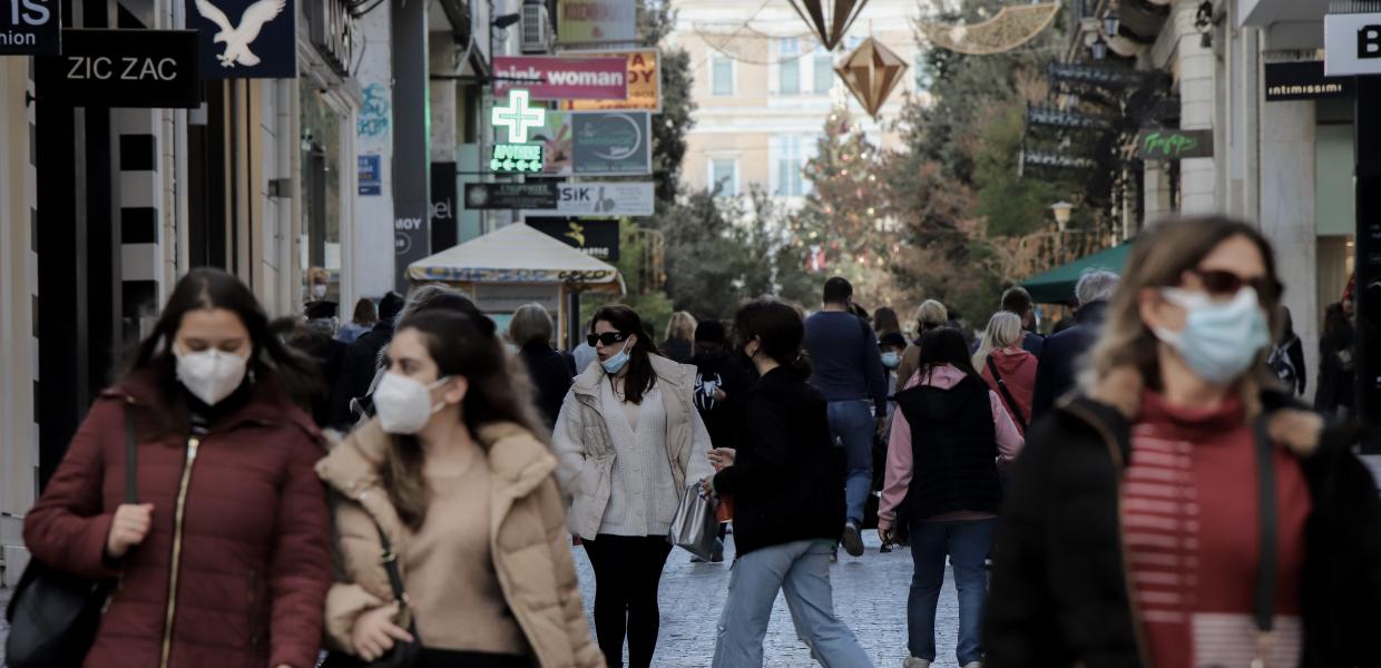 Άνθρωποι περπατούν στην Ερμου φορώντας μάσκα