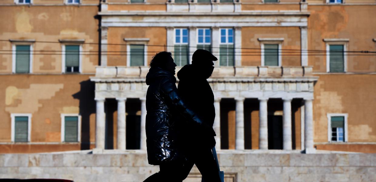 Άνθρωποι περπατούν μπροστά στη Βουλή