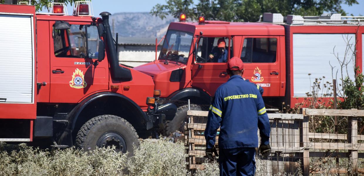 Πυροσβέστης και πυροσβεστικά οχήματα σε κατάσβεση φωτιάς