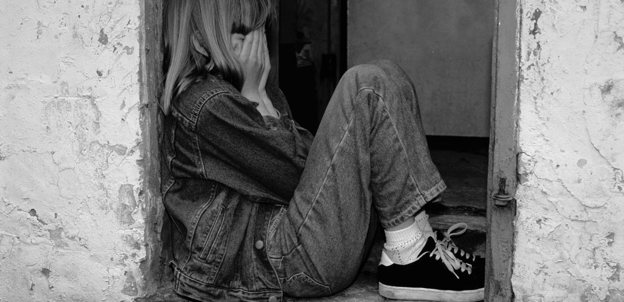 Κοριτσάκι φοβισμένο κάθεται με τις παλάμες στο πρόσωπό της 
