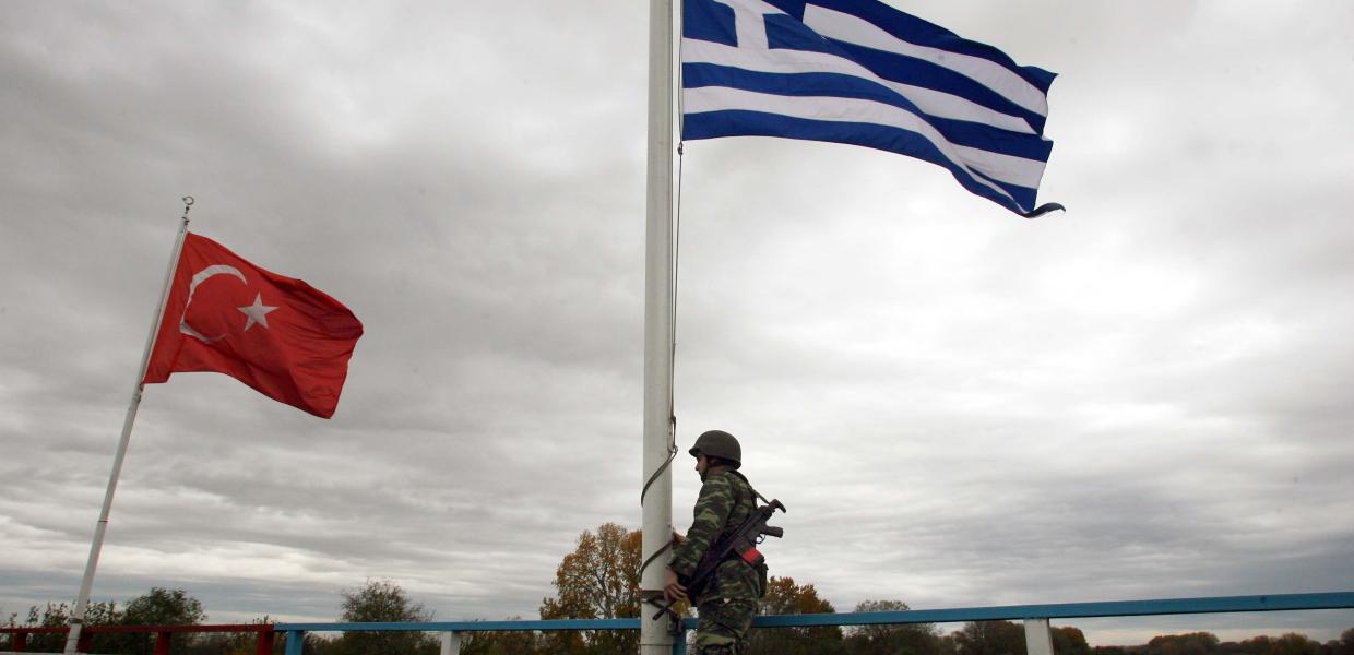 Στρατιώτης στα σύνορα με όπλο και σημαίες της Τουρκίας και της Ελλάδας