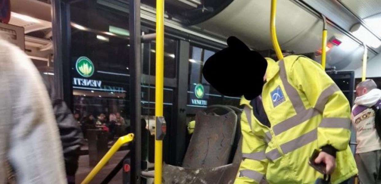 Άνδρας μαζεύει το κομμάτι της οροφής που έπεσε από τα καθίσματα του λεωφορείου