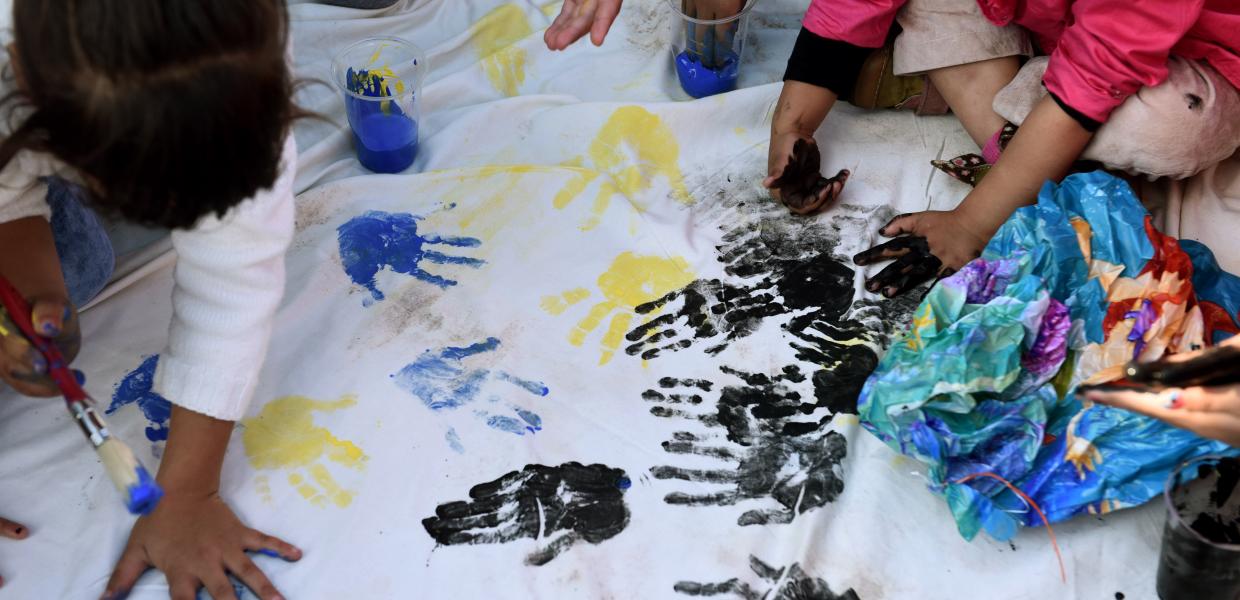 Προσφυγόπουλα ζωγραφίζουν παλάμες με τα χέρια τους