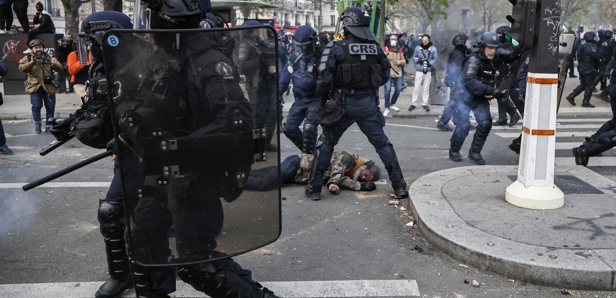 Αστυνομικοί με κράνη και αλεξίσφαιρα και ένας διαδηλωτής πεσμένος στον δρόμο στις διαδηλώσεις κατά της μεταρρύθμισης του συνταξιοδοτικού