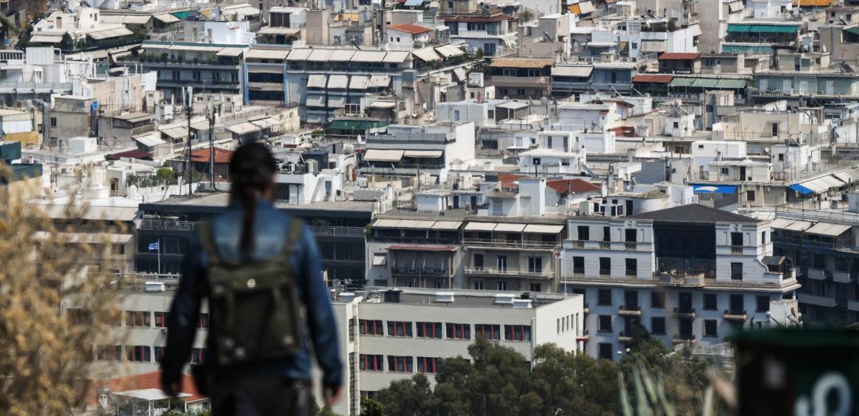 Κοπέλα γυρισμένη πλάτη με φόντο τις πολυκατοικίες στην Αθήνα