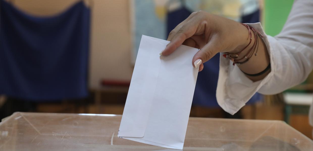 Χέρι γυναίκας που βάζει τον φάκελο μέσα στην εκλογική κάλπη