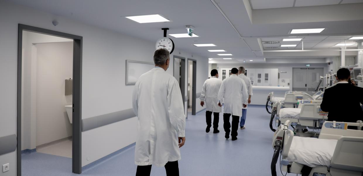 Γιατροί περπατούν μέσα σε θάλαμο νοσοκομείο με κρεβάτια σε δεξιά τους