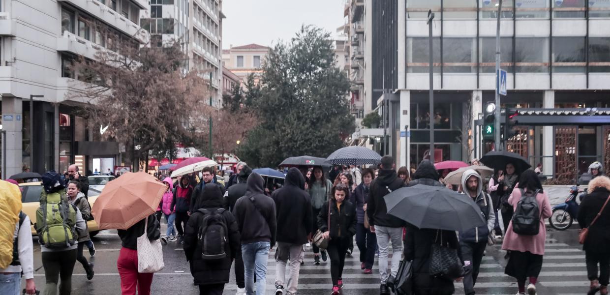 Κόσμος στο Σύνταγμα περνά την διάβασα κρατώντας ομπρέλες λόγω βροχής