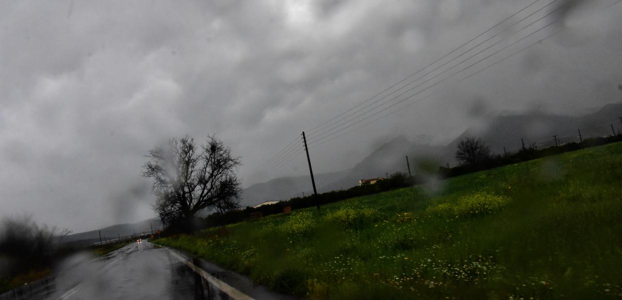 Ο ουρανός συννεφιασμένος ο δρόμος, πράσινο στα δεξιά και σταλαγματιές από τη βροχή πάνω στον φακό που τραβά την εικόνα 