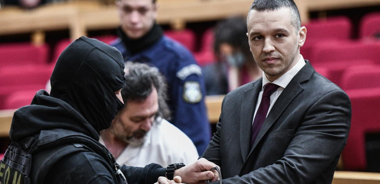 αστυνομικός βάζει τις χειροπέδες στον Κασιδιάρη στην αίθουσα του δικαστηρίου