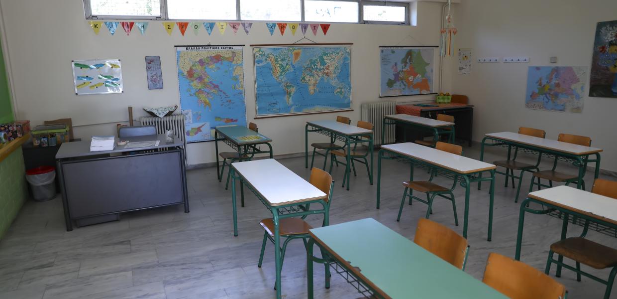 Άδεια σχολική αίθουσα με θρανία, την έδρα και χάρτες στους τοίχους