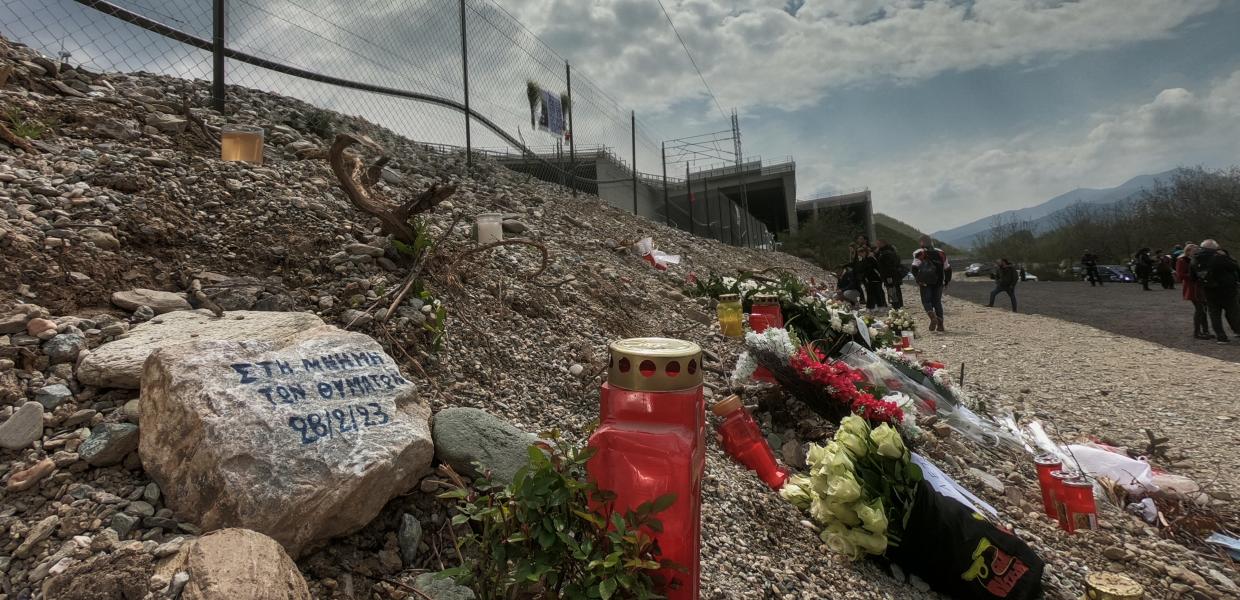 κεριά και λουλούδια στη μνήμη των θυμάτων των Τεμπών και ένα μήνυμα γραμμένο σε μια πέτρα