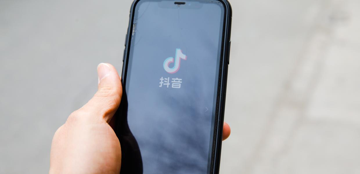 Χέρι κρατά κινητό με το λογότυπο του TikTok στην οθόνη