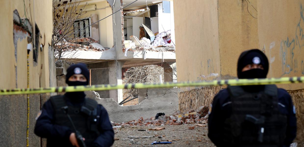 Τούρκοι αστυνομικοί με στολές και όπλα μπροστά από ερείπια και πίσω από κορδέλα