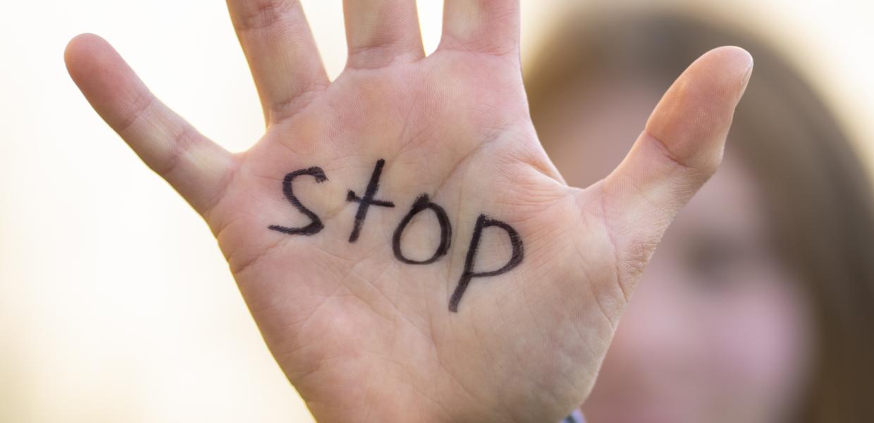 ανοιχτή παλάμη κοπέλας που γράφει την λέξη «Stop»