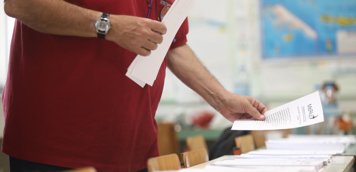 Άντρας τοποθετεί το ψηφοδέλτια στο θρανίο εκλογικού τμήματος