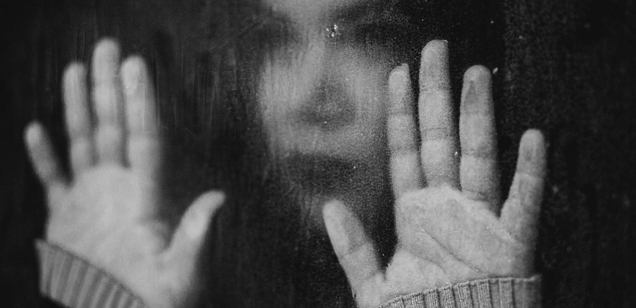 Ασπρόμαυρη φωτογραφία γυναίκας με τις παλάμες σε βρεγμένο τζάμι