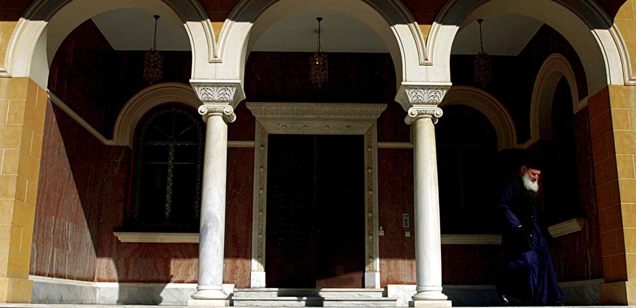 Κτίριο της Ιεράς Συνόδου Κύπρου με παπά να προχωρά στα σκαλιά 