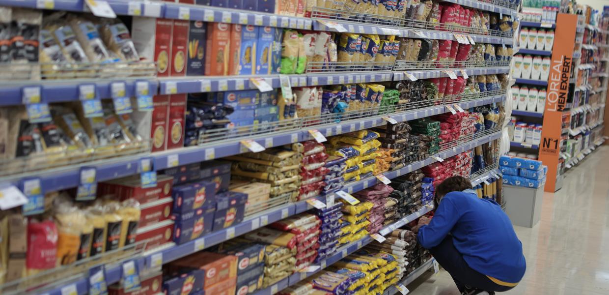 Εργαζόμενη σε διάδρομο σούπερ μάρκετ με προϊόντα