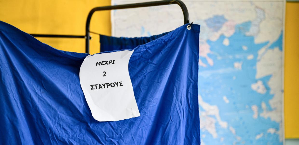 Παραβάν σε εκλογικό κέμντρο με χαρτί πάνω του που γράφει «μέχρι δύο σταυρούς»