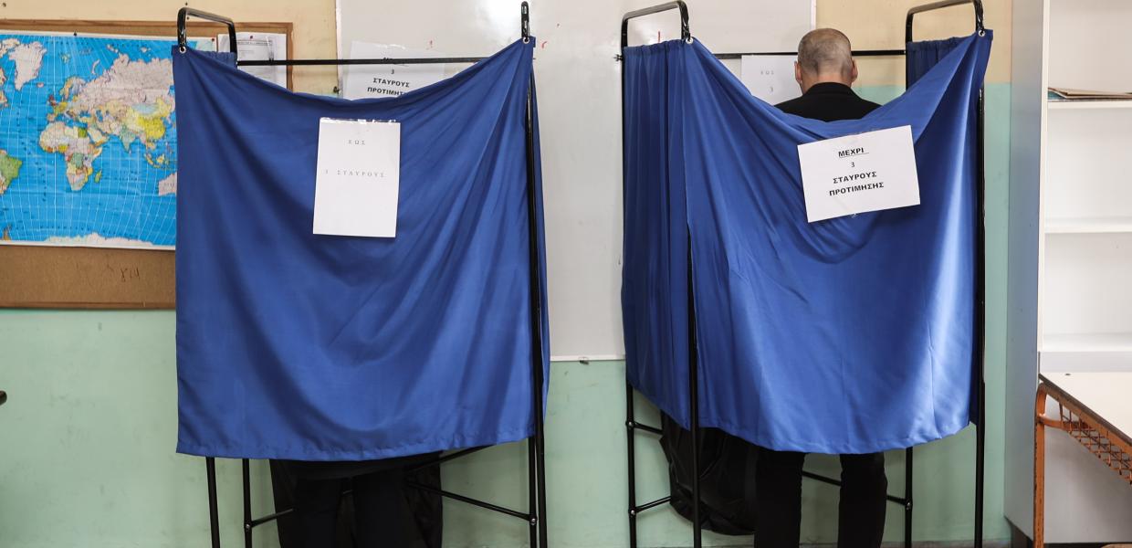 Ψηφοφόροι πίσω από το παραβάν σε εκλογικό κέντρο