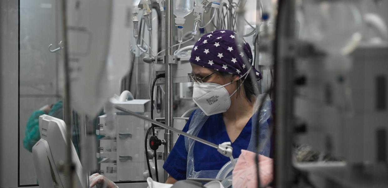 Γιατρός με μάσκα και σκουφάκι σε ΜΕΘ νοσοκομείου ανάμεσα σε μηχανήματα