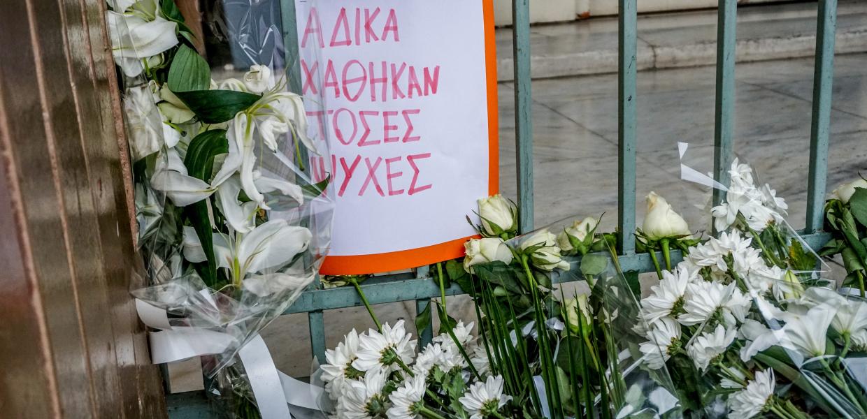 Λουλούδια στη μνήμη των νεκρών στα Τέμπη και ένα χαρτί που γράφει άδικα χάθηκαν τόσες ζωές»