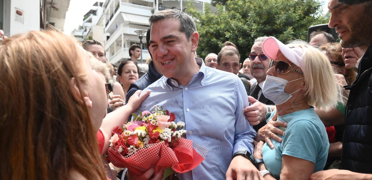 Ο Αλέξης Τσίπρας με μια ανθοδέσμη στα χέρια ανάμεσα σε κόσμο που τον χαιρετά