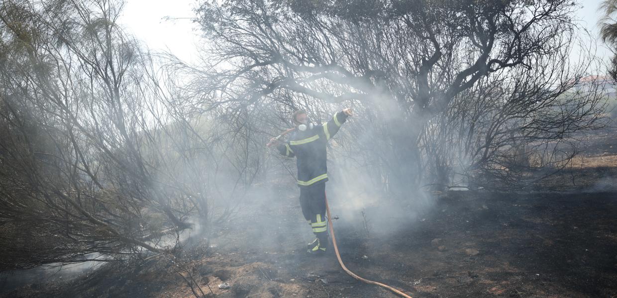 Πυροσβέστης με την μάνικα επιχειρεί σε σημείο που ξέσπασε φωτιά