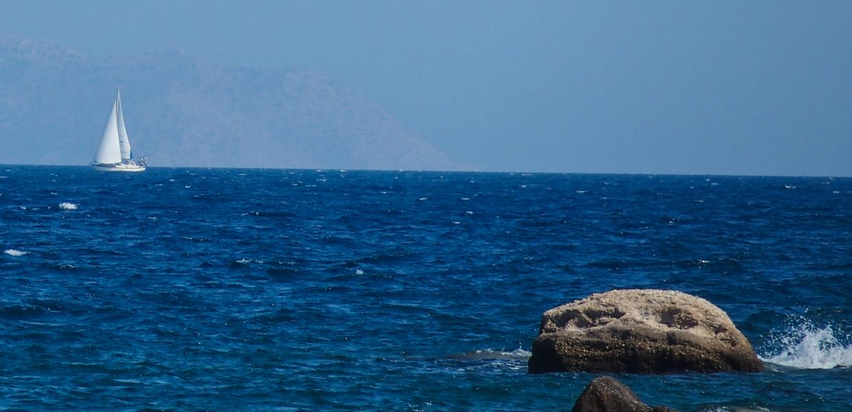 Θάλασσα με ένα ιστιοφόρο στο βάθος και έναν βράχο μπροστά