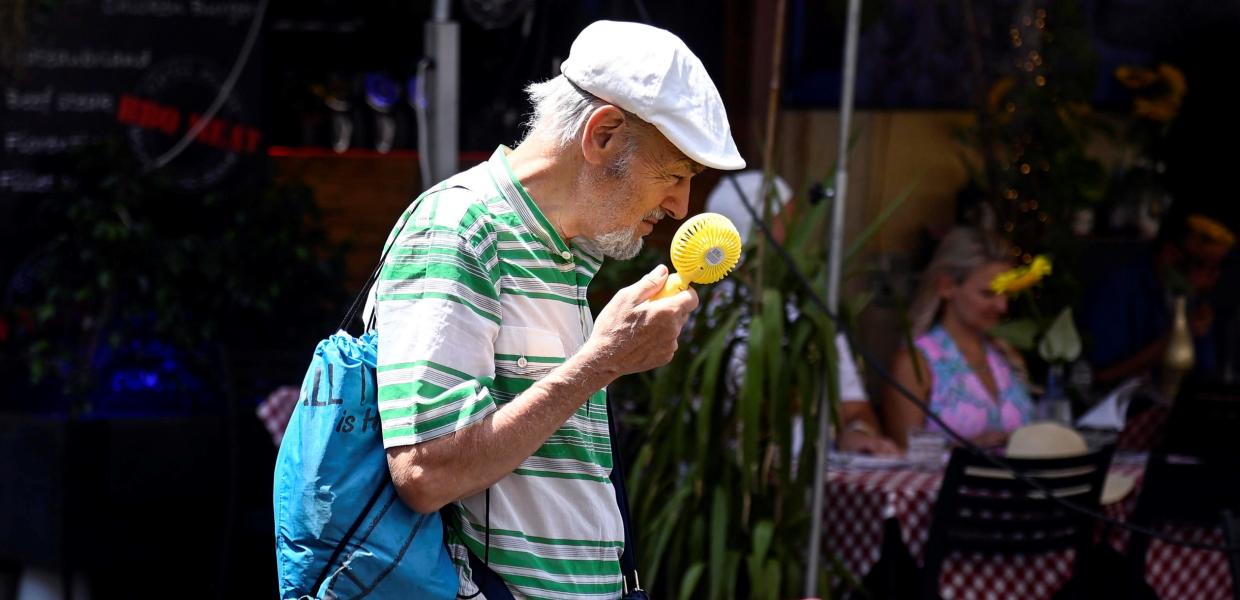 Ηλικιωμένος κρατάει στο χέρι ανεμιστηράκι για τη ζέστη