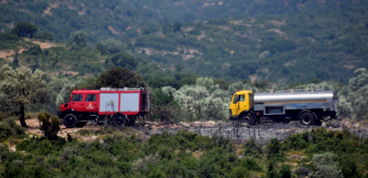 πυροσβεστικό και πίσω υδροφόρα κινούνται σε δρόμο μέσα σε χαμηλή βλάστηση