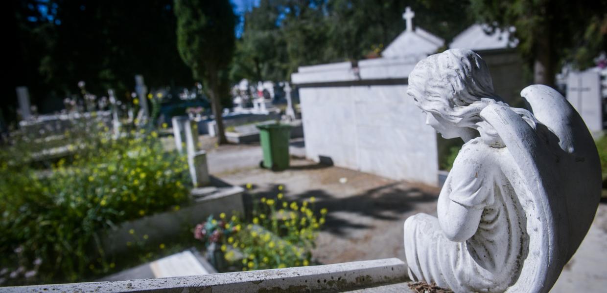 Μαρμάρινο άγαλμα αγγέλου σε νεκροταφείο και πίσω τα μνήματα
