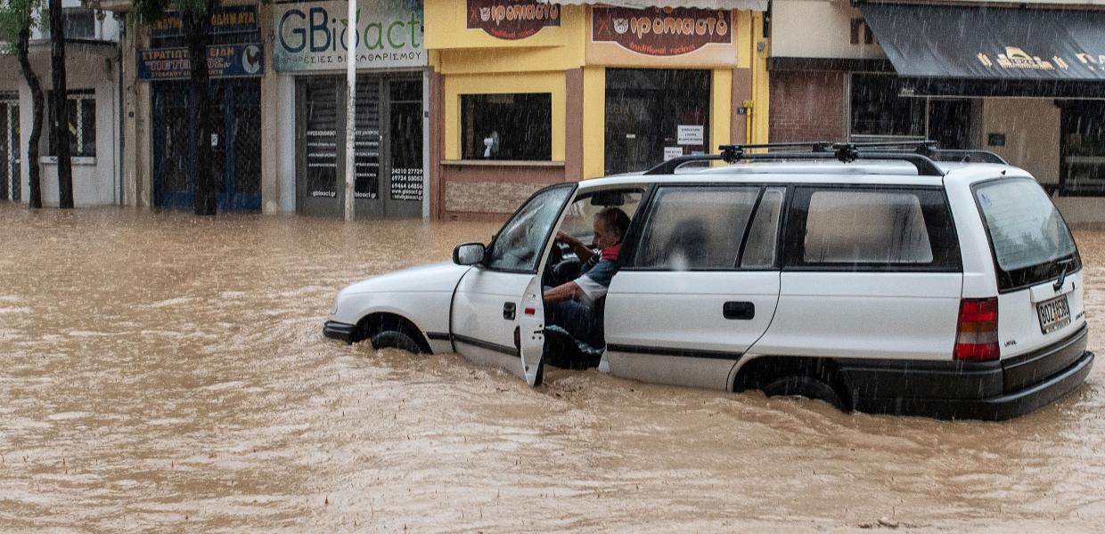 Πολίτης προσπαθεί να βγεί από το αυτοκίνητό του σε πλημμυρισμένο δρόμο στο Βόλο