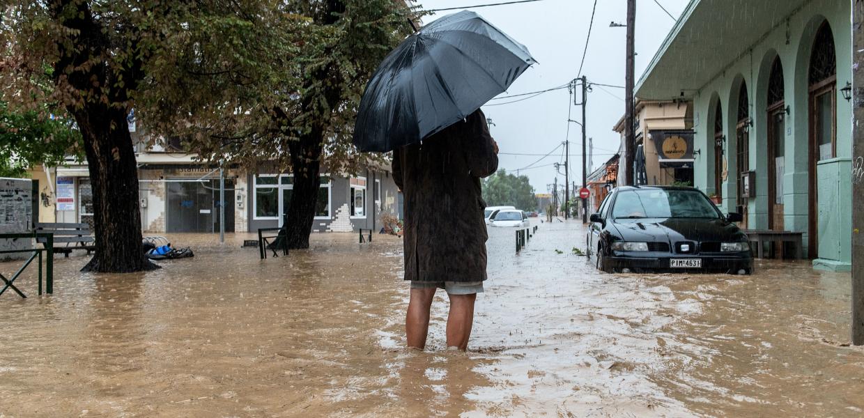 Πολίτης περπατά σε πλημμυρισμένο δρόμο στο Βόλο,