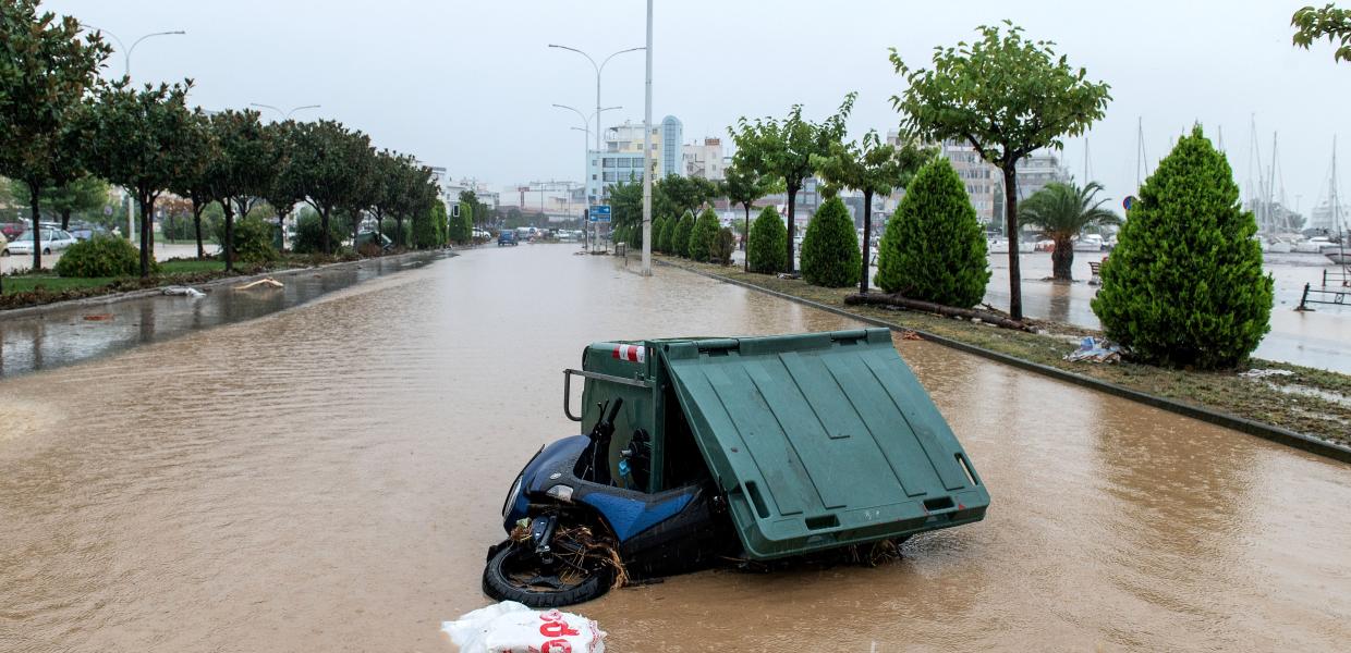 Πεσμένο μηχανάκι μπλεγμένο σε κάδο σκουπιδιών σε πλημμυρισμένο δρόμο στο Βόλο