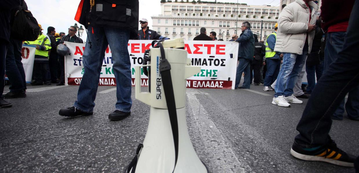 Ντουντούκα μπροστά από πανό σε πορεία διαμαρτυρίας