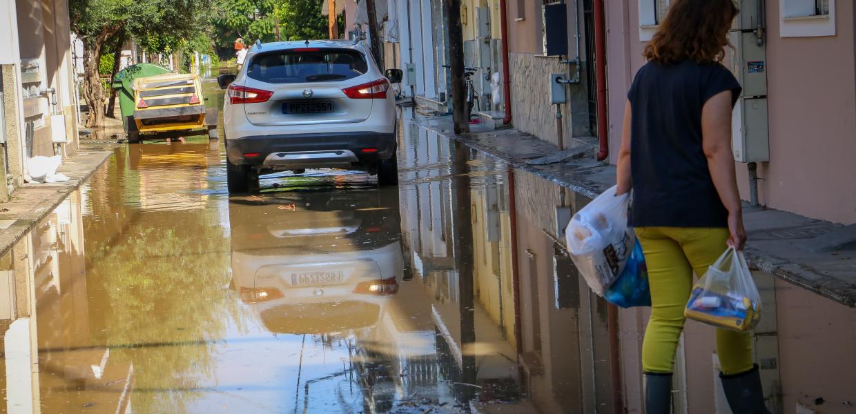 Γυναίκα με σακούλες στο χέρι σε πλημμυρισμένο δρόμο