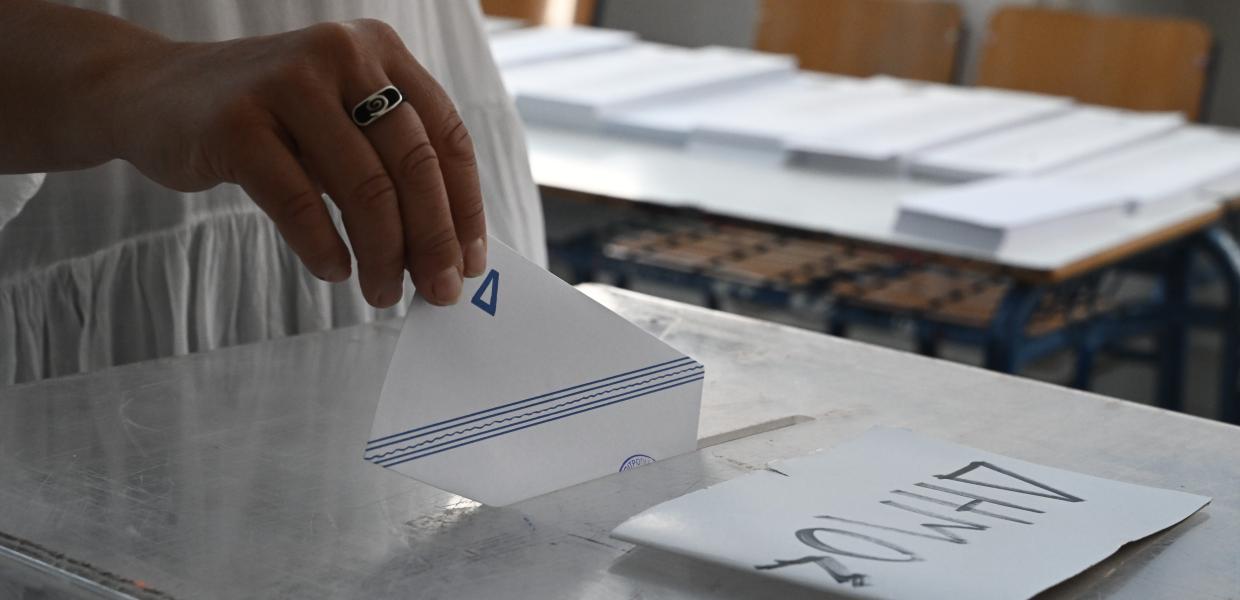 Χέρι γυναίκας βάζει φάκελο σε κάλπη