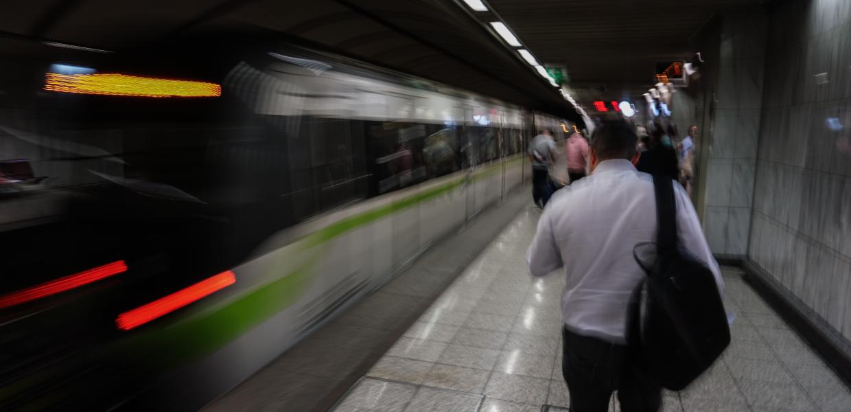 Άντρας με τσάντα στην πλάτη περπατά σε σταθμό του Μετρό την ώρα που φτάνει το τρενο