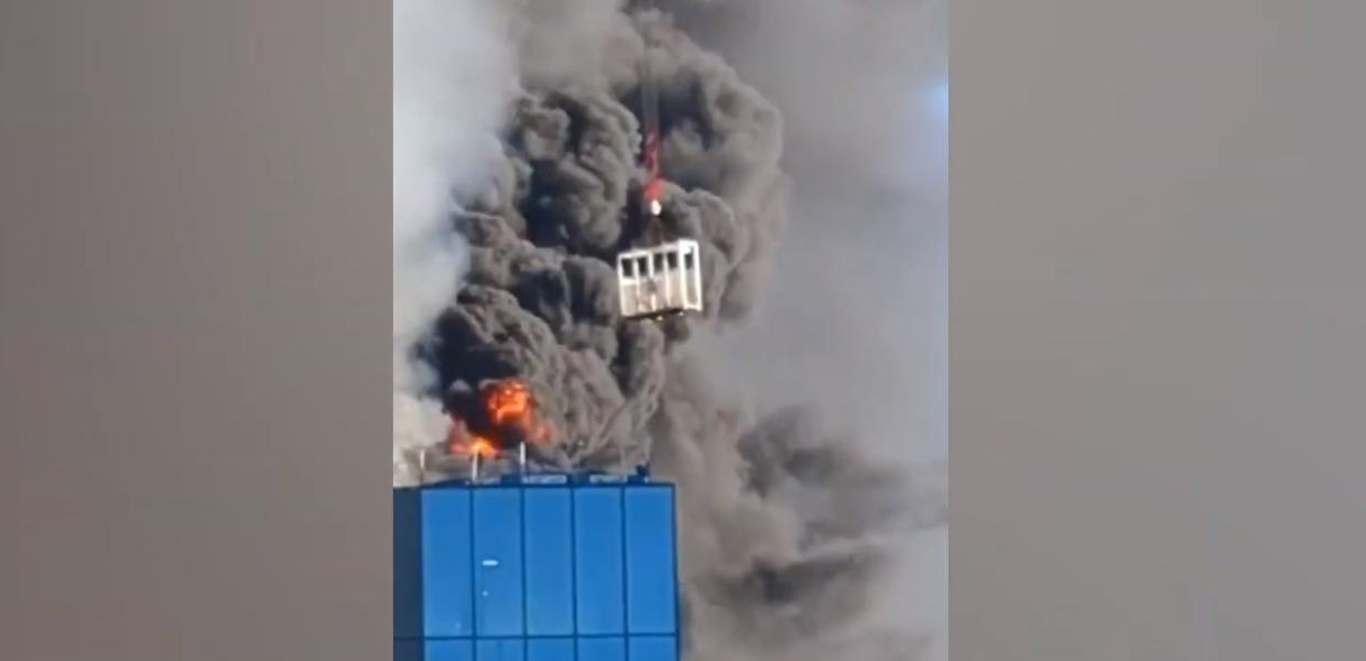 Η στιγμή που γερανός διασώζει τον άντρα από την οροφή του πολυώροφου κτιρίου με μαύρο καπνό να έχει σκεπάσει το σημείο