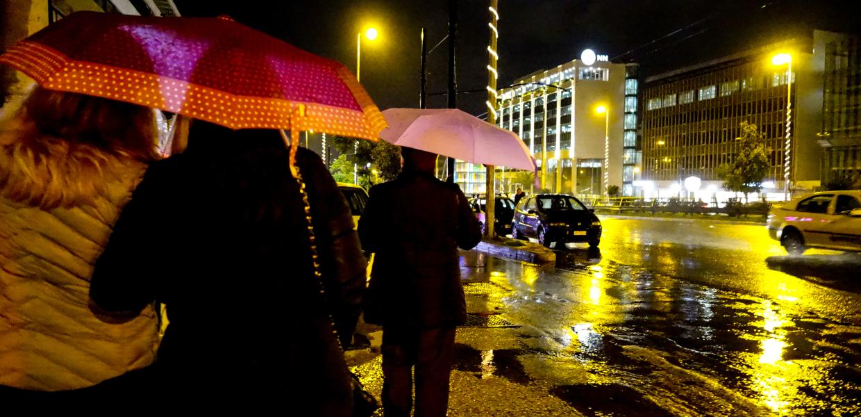 Κόσμος με ομπρέλες το βράδυ στην Αθήνα