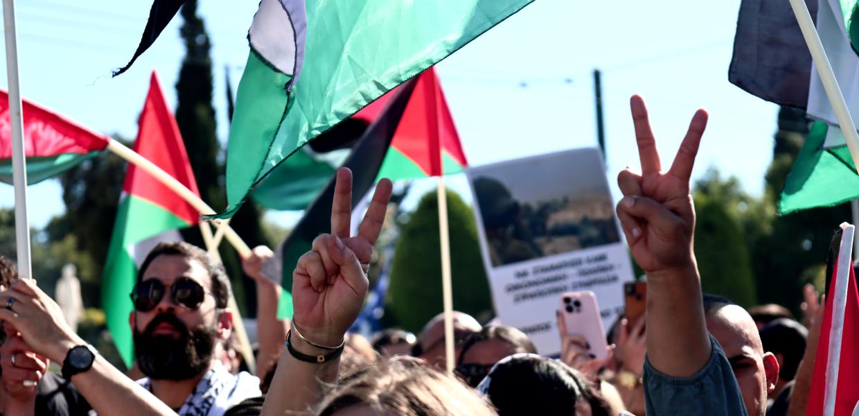 Κόσμος με σημαίες της Παλαιστίνης και κάνοντας το σήμα της νίκης διαδηλώνει για την σφαγή στη Γάζα